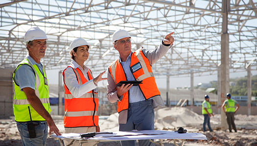 Three construction workers engaging in a discussion at a construction site