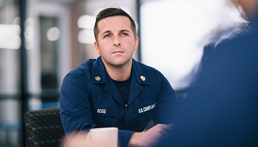A US Coast Guard member sitting in a room with his colleague