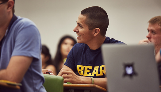 A student smiles while sitting in a classroom