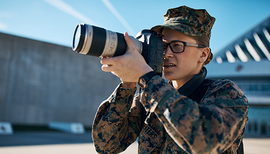 A Marine Corps service member shoots with a professional camera