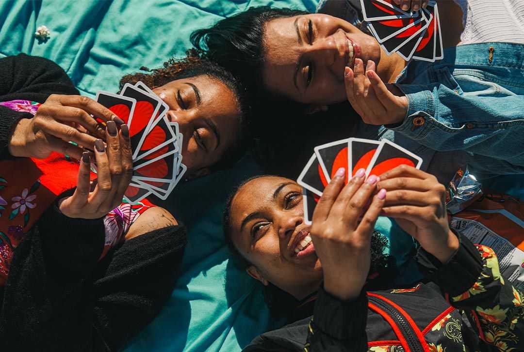 Three friends lying down and playing uno cards