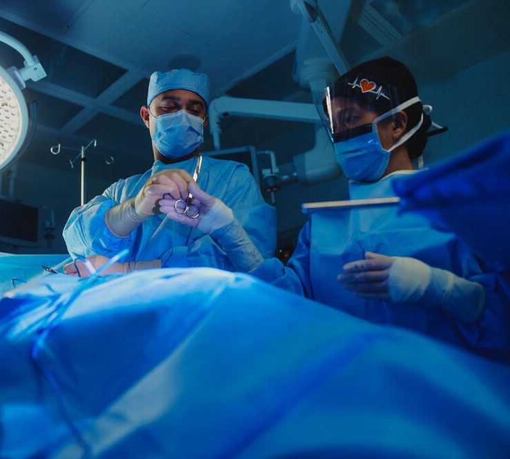 Two surgeons in scrubs perform a surgery on a patient