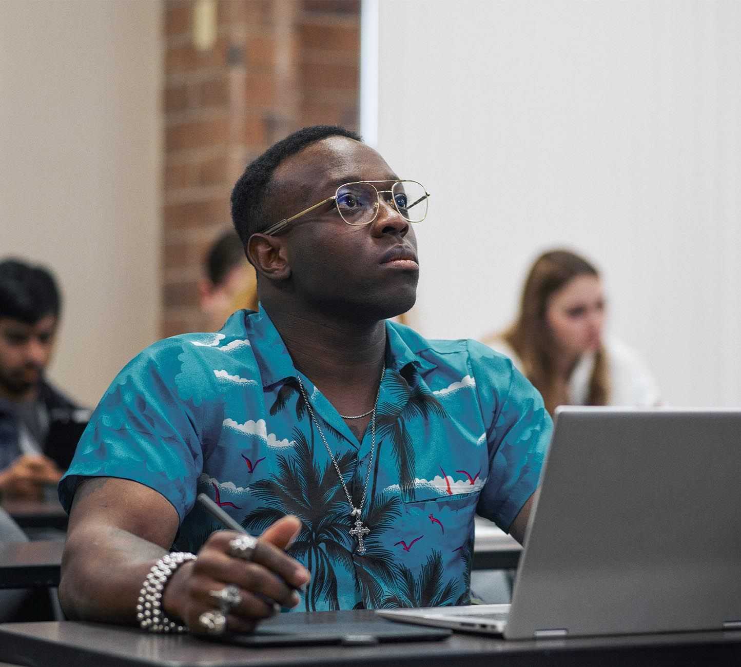 A young man wearing glasses in front of a laptop engaged with a presentation