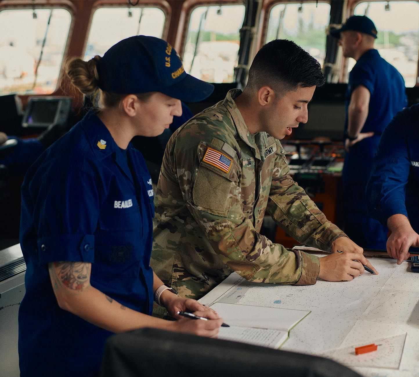 Two uniformed individuals discussing a map and taking notes