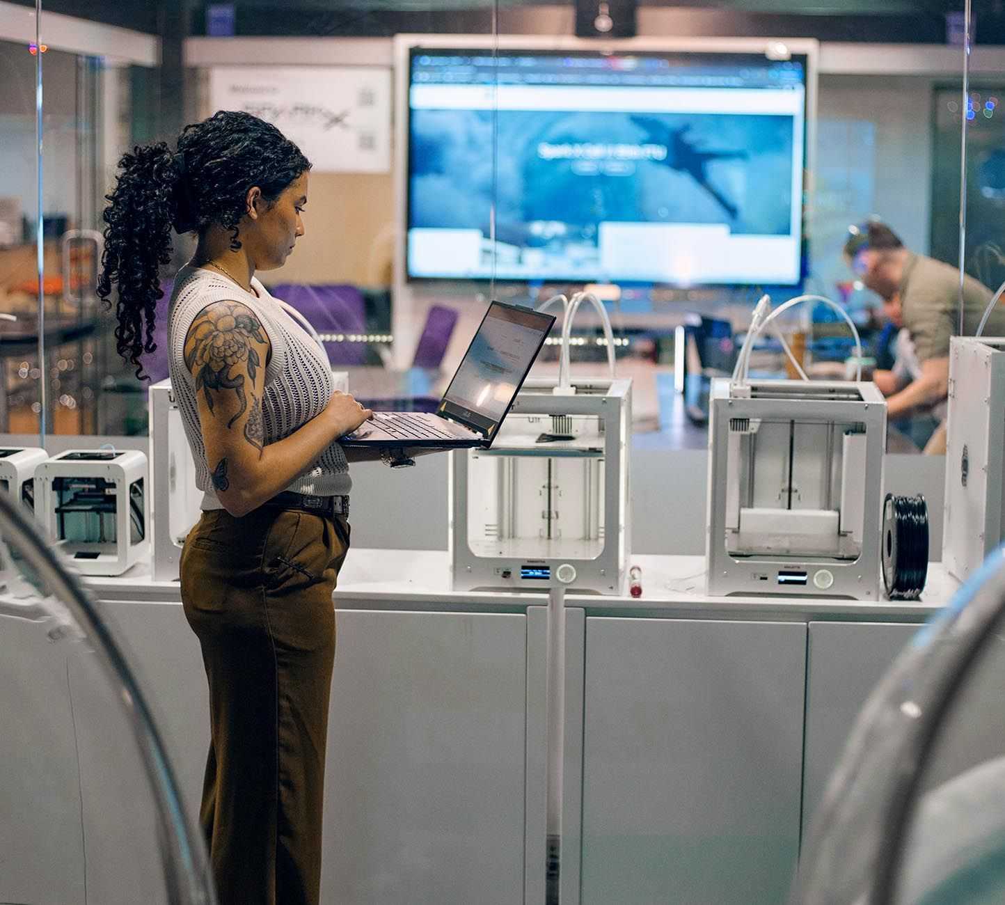 A woman is positioned before a large screen, working on a laptop in a scientific setting
