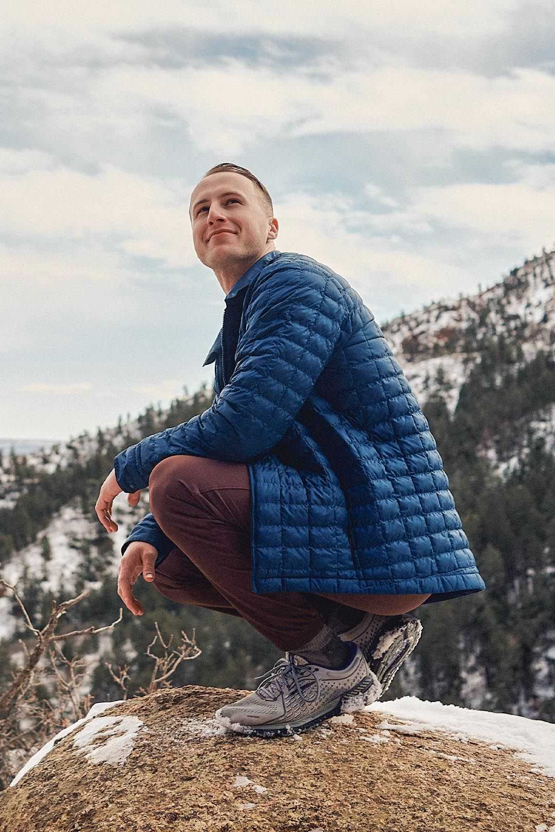 Young man kneeling on a rock in an outdoor setting