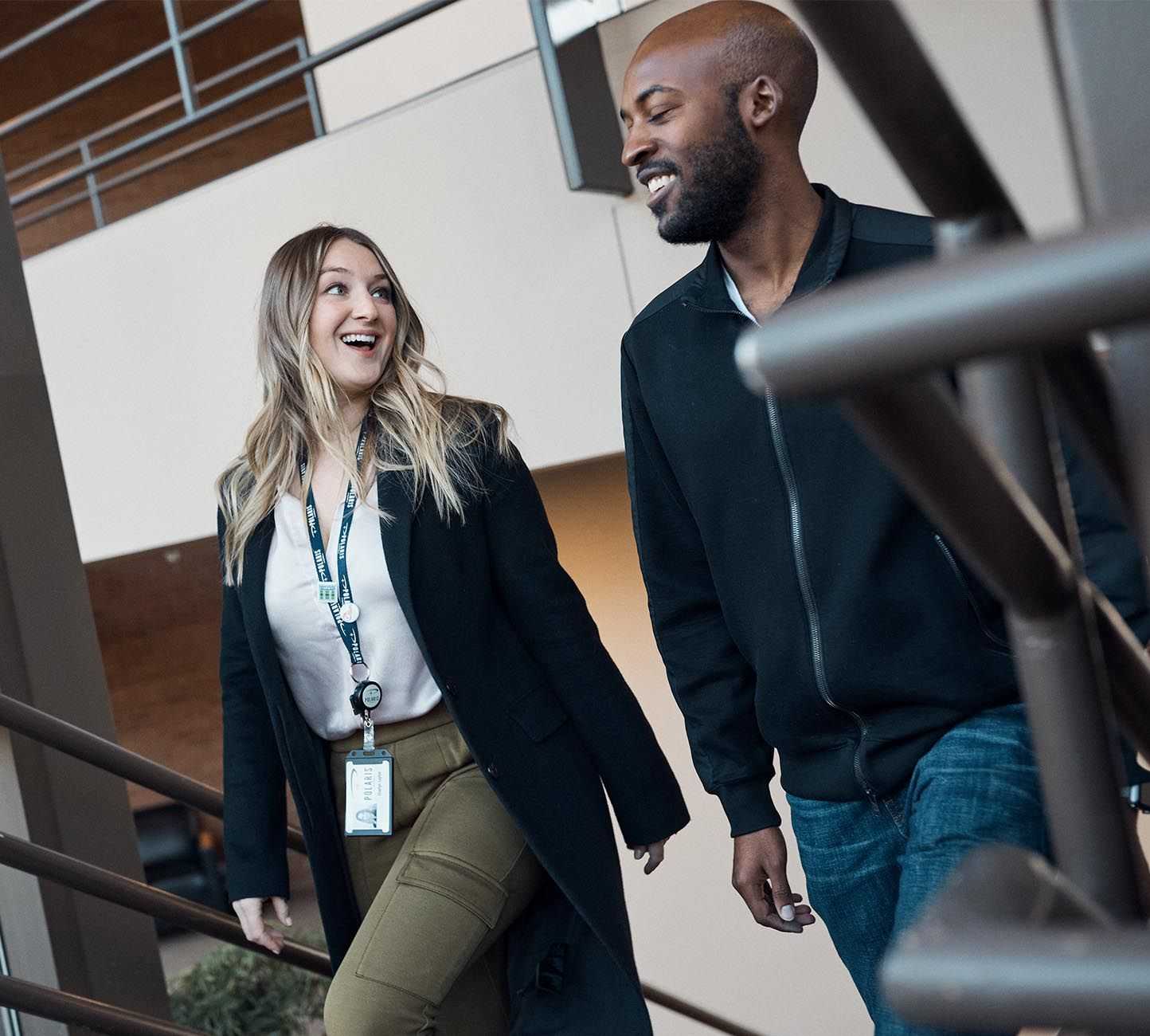 A man and a woman walk up the stairs smiling and chatting